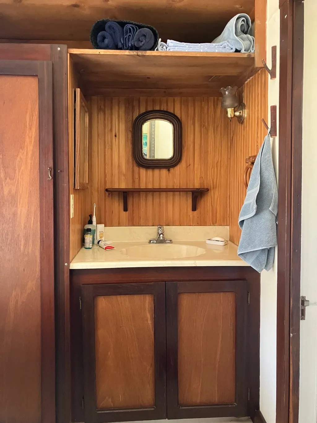 The bathroom sink set into a warm redwood nook with a small mirror and towels