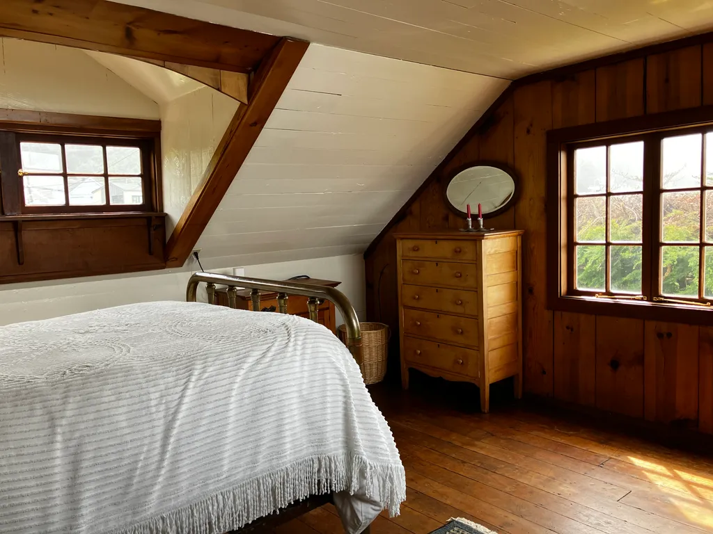 The upstairs bedroom with a brass bedstead beneath knotty pine panelling