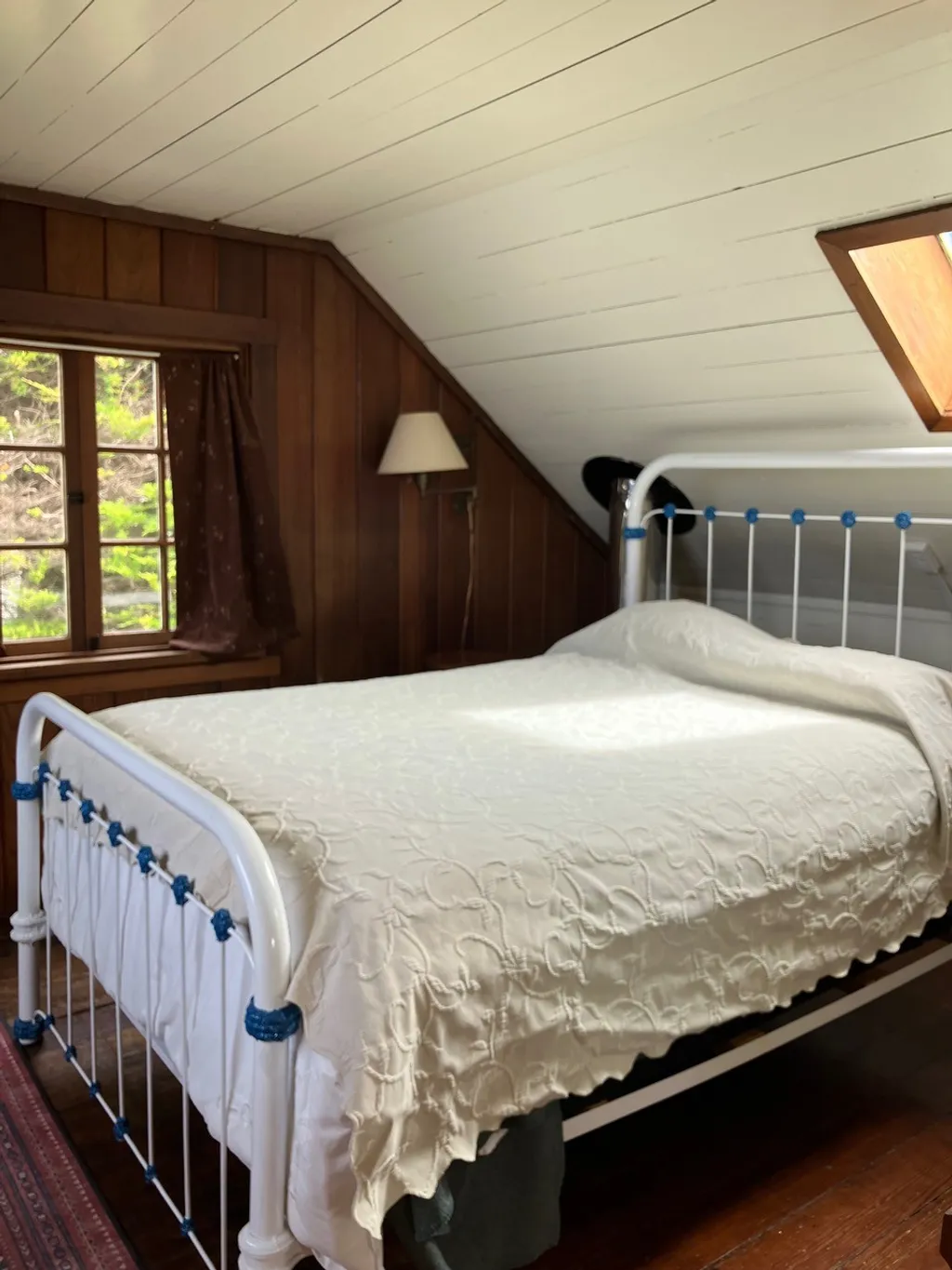 The second upstairs bedroom from the foot of the bed, with a skylight in the sloped ceiling