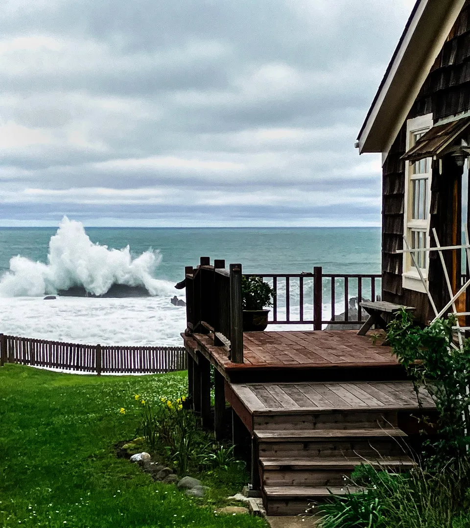 The redwood deck of the Westport House above a breaking Pacific wave