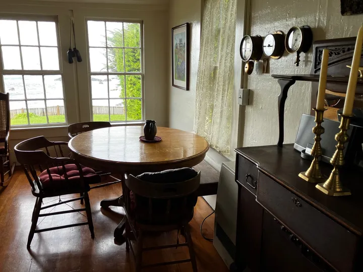 The dining room, its oak table and brass candlesticks framed by ocean-facing windows