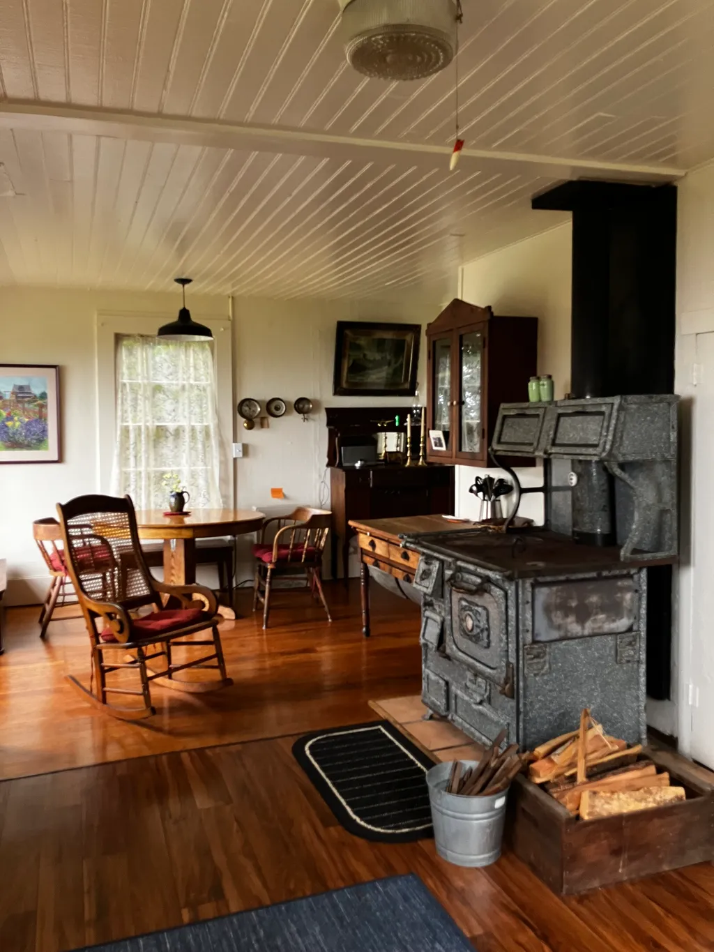 The dining room with a cast-iron cookstove, oak table, and sea-facing windows