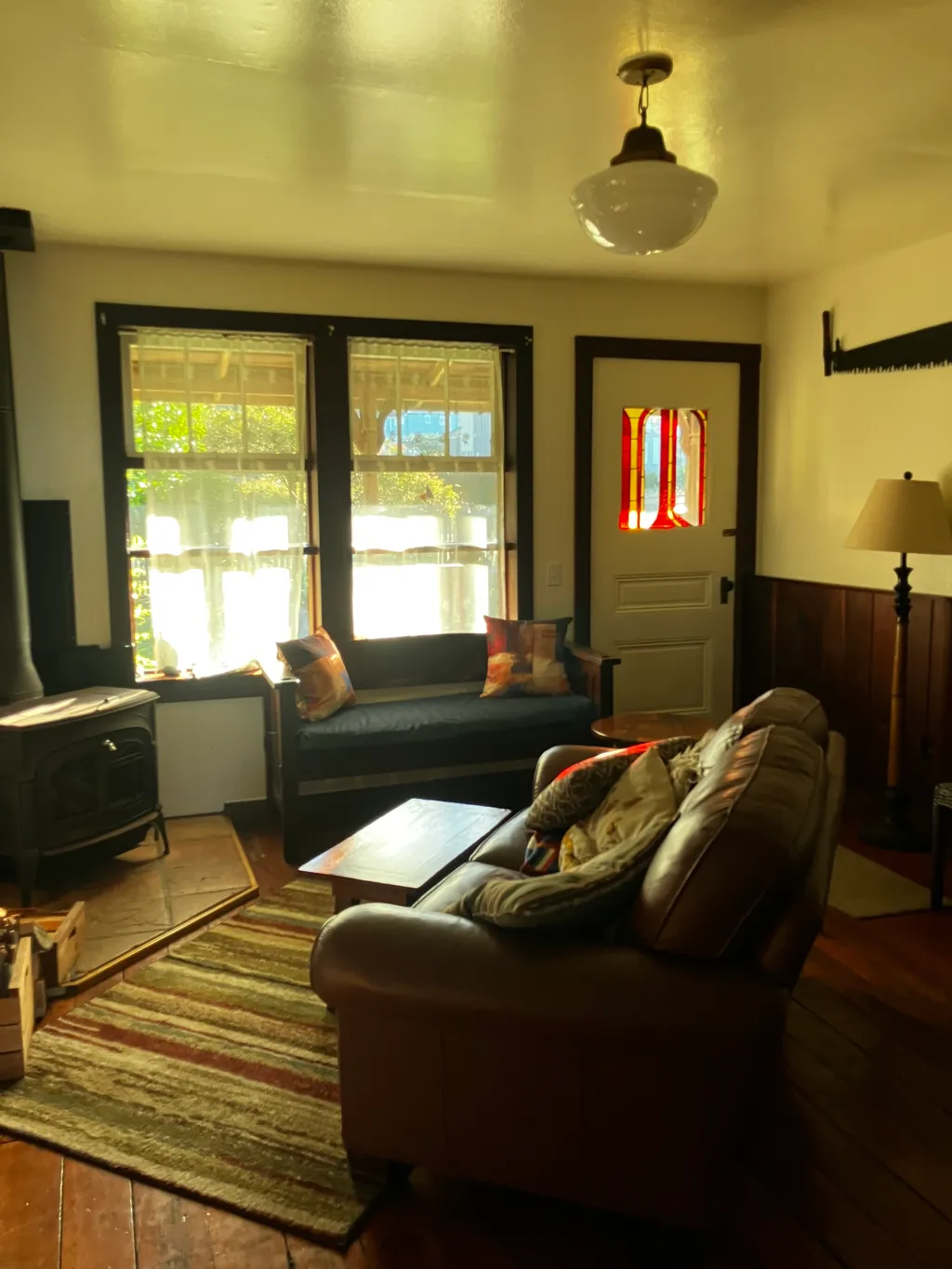 The living room with a wood stove, window seat, and a stained-glass door